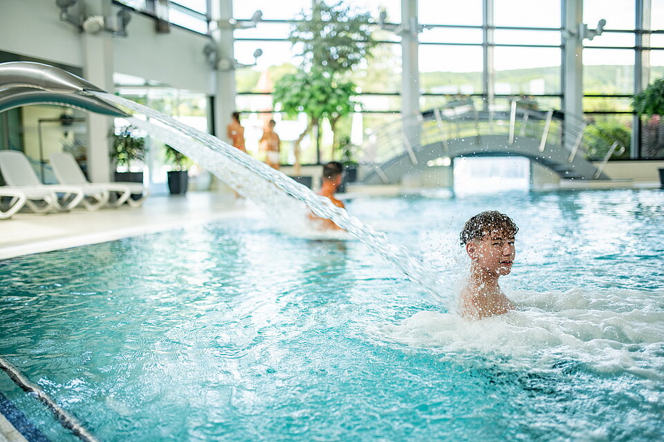 Vater und Sohn stehen unter der Nackenschwall-Dusche im Sole-Innenbecken