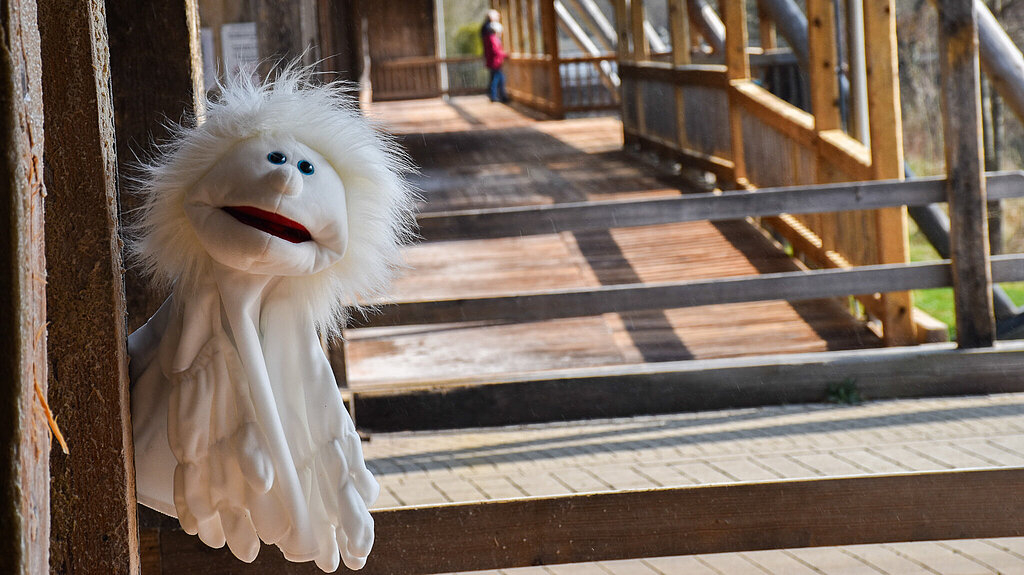 Handpuppe in der Gestalt eines weißen Gespenstes. Das Gespenst schwebt über den Boden am Gradierwerk.