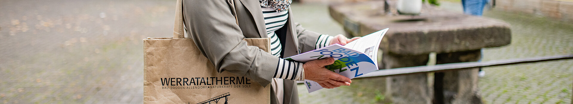 Eine Frau schaut sich eine Broschüre an. Ihr Mann steht am Salztisch.